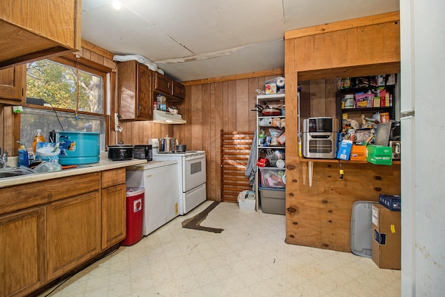 kitchen featuring white electric range oven, sink, exhaust hood, and wooden walls