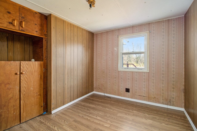 unfurnished room featuring light hardwood / wood-style floors and wooden walls