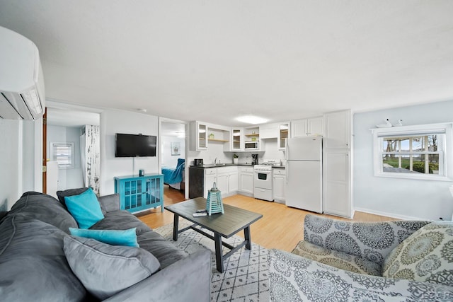 living room with light hardwood / wood-style flooring, a wall unit AC, and sink