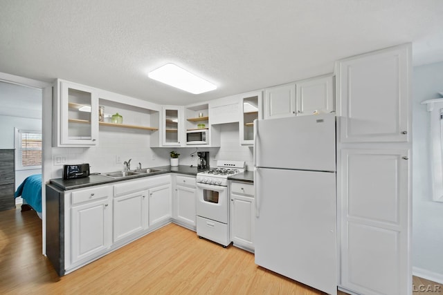 kitchen with white appliances, backsplash, sink, light hardwood / wood-style floors, and white cabinetry