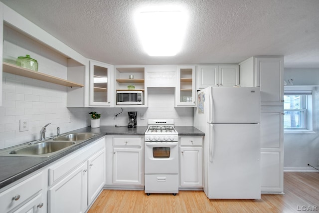 kitchen with white appliances, backsplash, white cabinets, sink, and light hardwood / wood-style floors