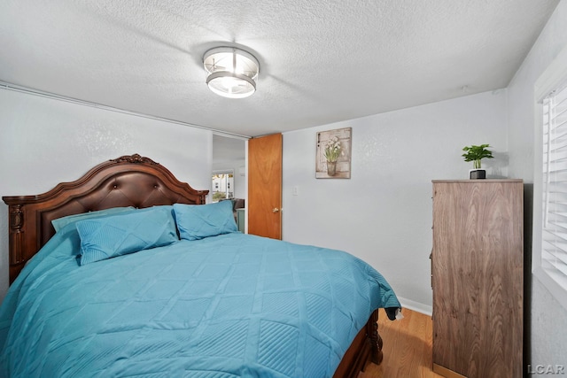 bedroom with wood-type flooring, a textured ceiling, and multiple windows