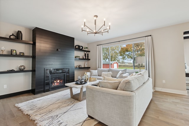 living room featuring a notable chandelier, a fireplace, light wood-type flooring, and baseboards