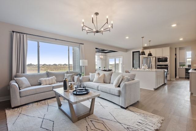 living room featuring recessed lighting, a notable chandelier, plenty of natural light, and light wood-style floors