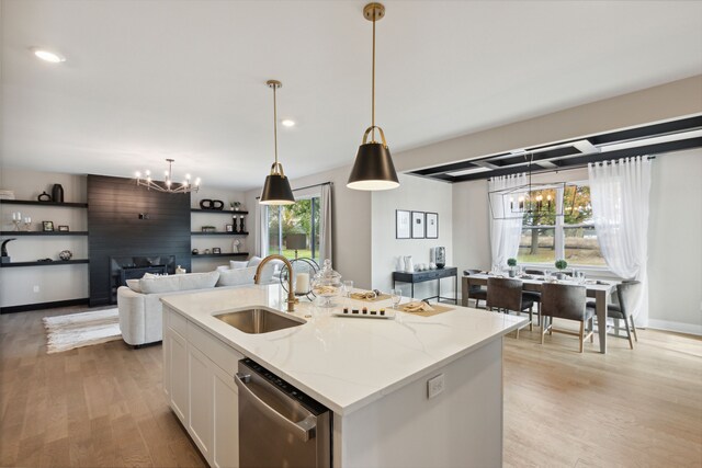 kitchen with light stone counters, stainless steel dishwasher, a kitchen island with sink, white cabinets, and light wood-type flooring