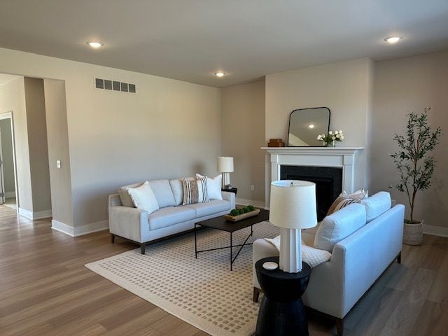 living area featuring visible vents, baseboards, wood finished floors, and a fireplace