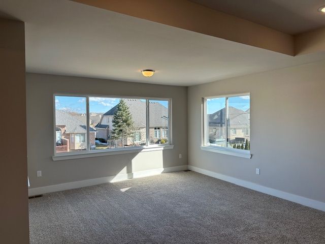 carpeted spare room featuring baseboards