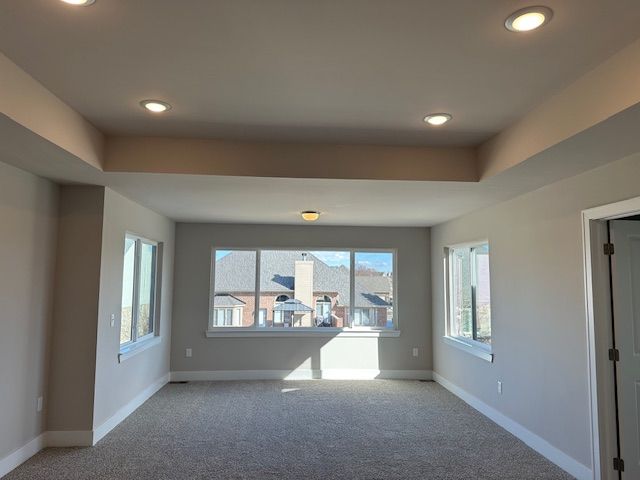 carpeted empty room featuring a raised ceiling, recessed lighting, and baseboards