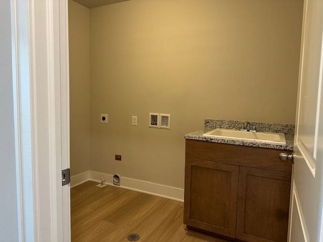 clothes washing area with hookup for a washing machine, hookup for an electric dryer, laundry area, light wood-style flooring, and a sink