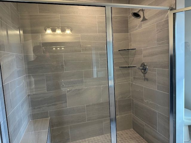 full bath featuring a shower stall and toilet