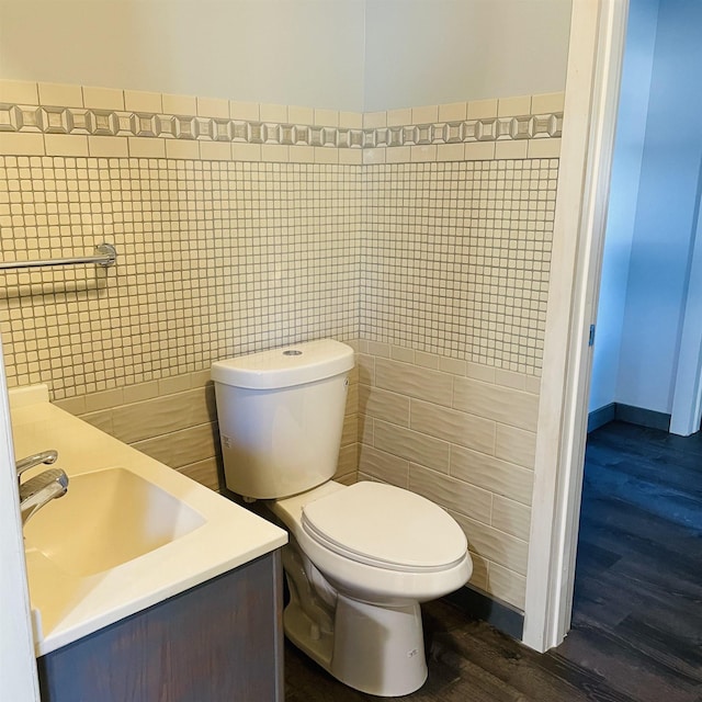 bathroom featuring vanity, wood-type flooring, toilet, and tile walls