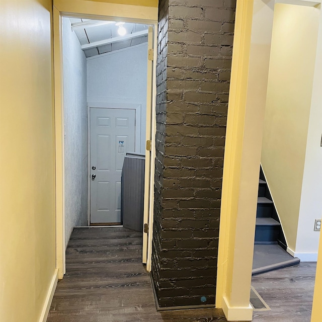 hallway featuring brick wall and dark hardwood / wood-style floors