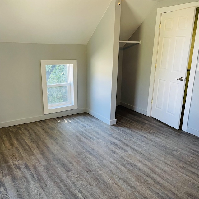 unfurnished bedroom with vaulted ceiling and dark hardwood / wood-style flooring