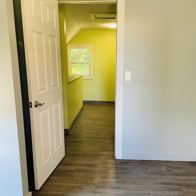 hall with dark wood-type flooring and vaulted ceiling