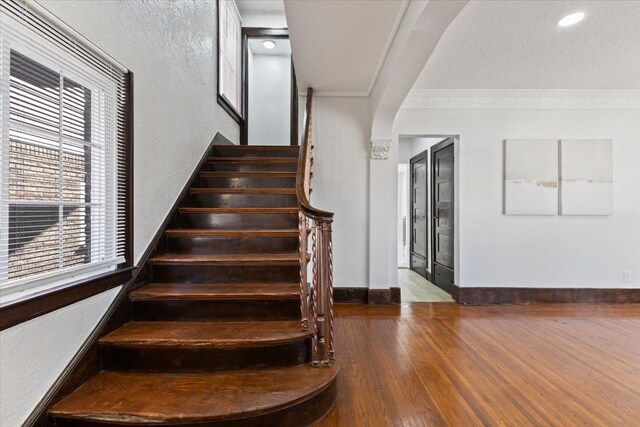 stairway with hardwood / wood-style flooring and ornamental molding