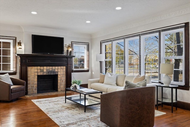 living room featuring a fireplace, ornamental molding, a textured ceiling, and hardwood / wood-style flooring