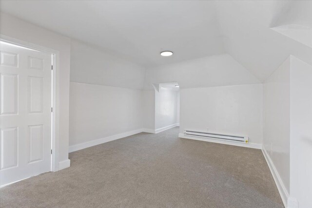 additional living space with light carpet, a baseboard radiator, and vaulted ceiling