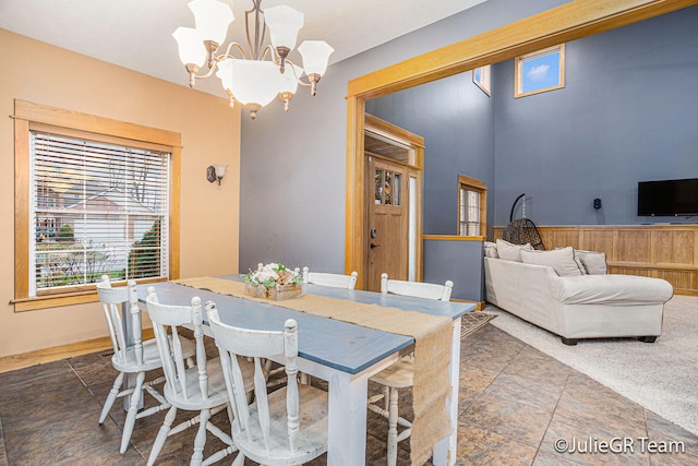 dining area with a notable chandelier and wood walls