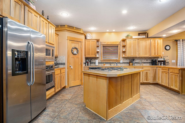 kitchen featuring backsplash, a textured ceiling, and appliances with stainless steel finishes