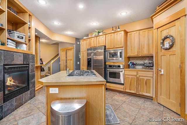 kitchen with a kitchen breakfast bar, tasteful backsplash, stainless steel appliances, a tile fireplace, and a kitchen island