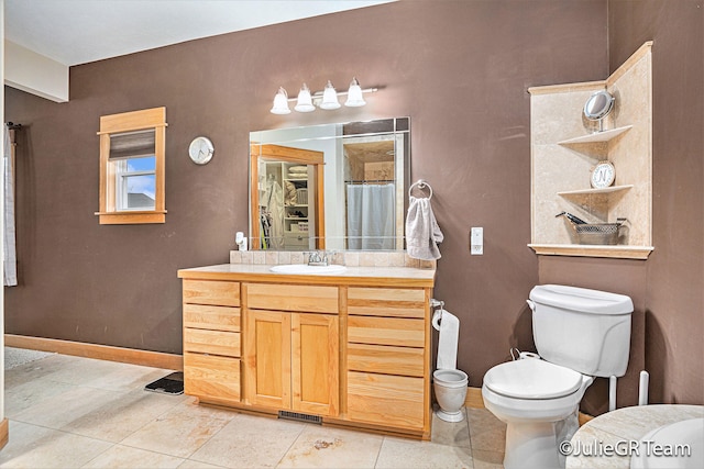 bathroom featuring tile patterned floors, vanity, toilet, and walk in shower