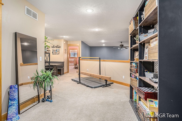 exercise room with carpet flooring, a textured ceiling, and ceiling fan