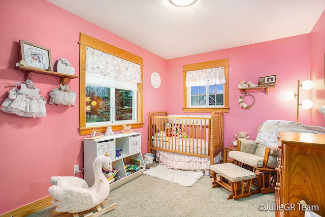 bedroom with a crib, carpet floors, and multiple windows