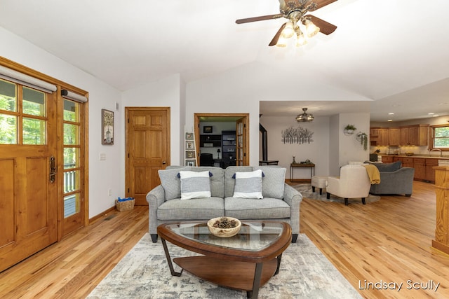 living room featuring light wood-type flooring, ceiling fan, lofted ceiling, and sink