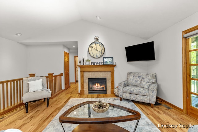 sitting room featuring a tile fireplace, lofted ceiling, and light wood-type flooring