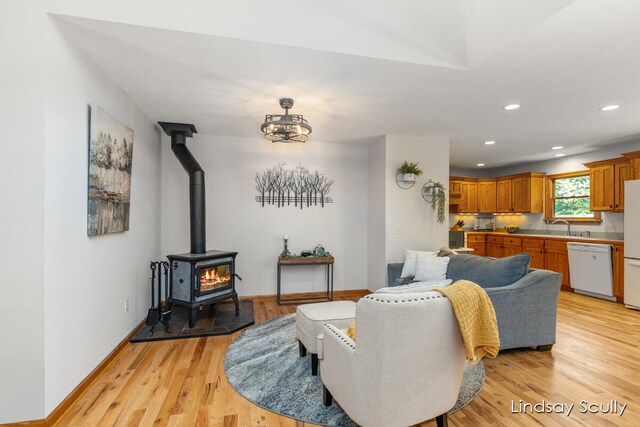 living room with light hardwood / wood-style floors, a wood stove, and sink