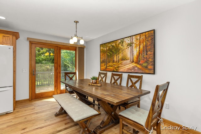 dining space with light hardwood / wood-style floors and an inviting chandelier