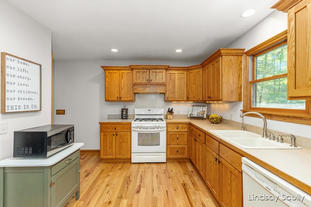 kitchen with sink, white appliances, and light hardwood / wood-style flooring