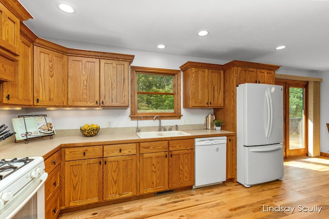 kitchen featuring light wood-type flooring, white appliances, plenty of natural light, and sink