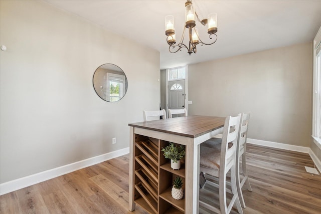 dining area with hardwood / wood-style flooring and a notable chandelier