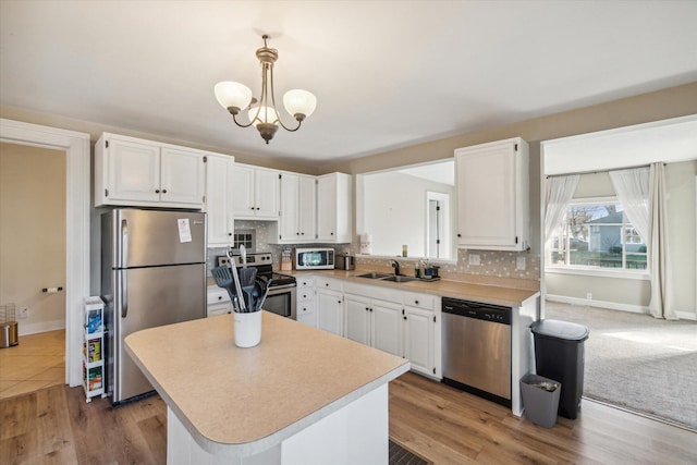 kitchen with stainless steel appliances, backsplash, pendant lighting, wood-type flooring, and white cabinets