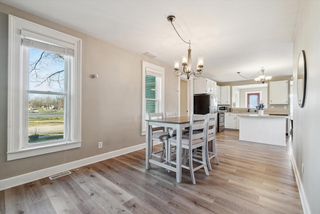 dining area with a chandelier and light hardwood / wood-style flooring