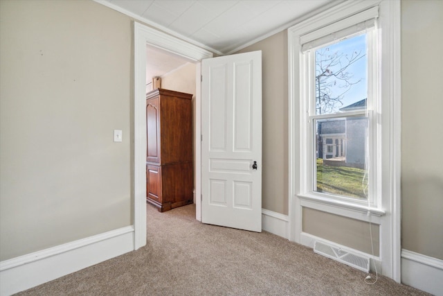 unfurnished bedroom with light colored carpet, ornamental molding, and multiple windows