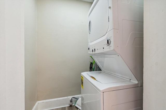 laundry room featuring hardwood / wood-style floors and stacked washer / drying machine