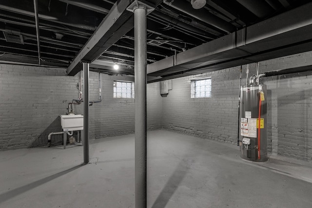 basement with sink, a wealth of natural light, and water heater