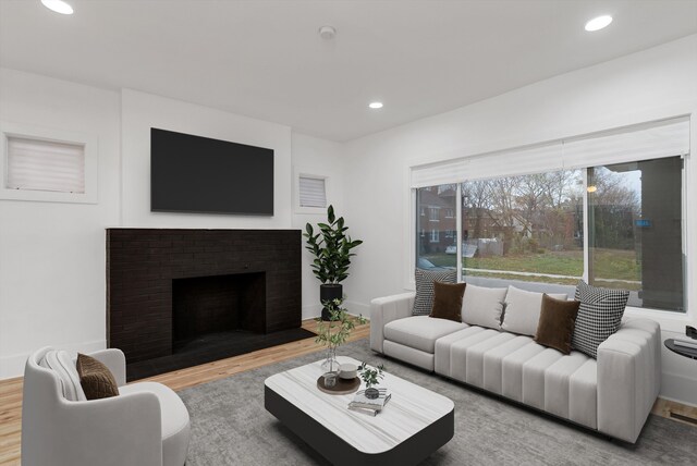 living room with wood-type flooring and a brick fireplace