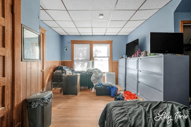 bedroom with a paneled ceiling, wood walls, and wood-type flooring