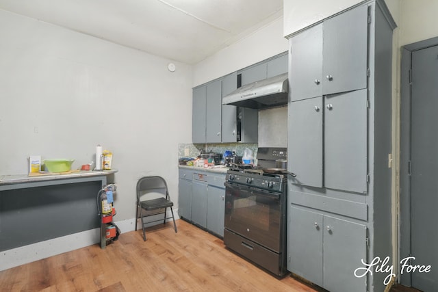 kitchen featuring decorative backsplash, gray cabinets, light wood-type flooring, gas stove, and extractor fan