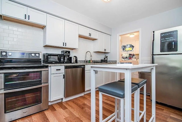 kitchen with white cabinets, appliances with stainless steel finishes, and light wood-type flooring