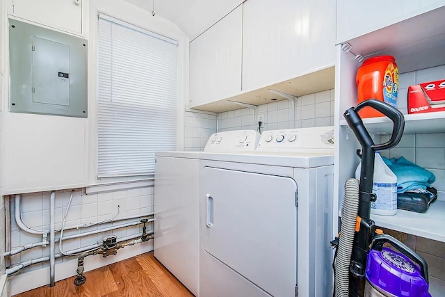 laundry room with electric panel, washer and clothes dryer, cabinets, and light wood-type flooring