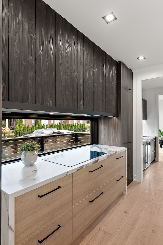 kitchen with stainless steel dishwasher, light hardwood / wood-style floors, and cooktop