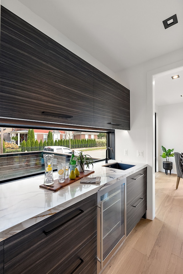 kitchen with light hardwood / wood-style floors, plenty of natural light, beverage cooler, and sink