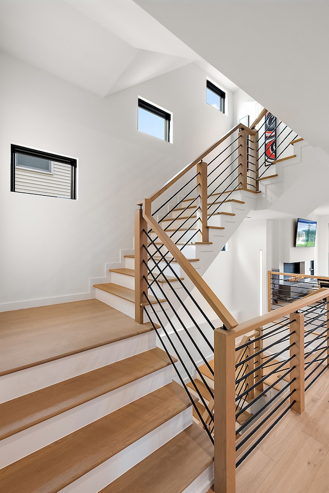 stairs with a towering ceiling and hardwood / wood-style flooring