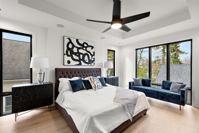 bedroom with a tray ceiling, ceiling fan, and hardwood / wood-style flooring