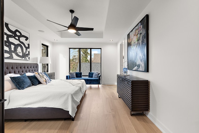 bedroom featuring ceiling fan, light hardwood / wood-style floors, and a raised ceiling