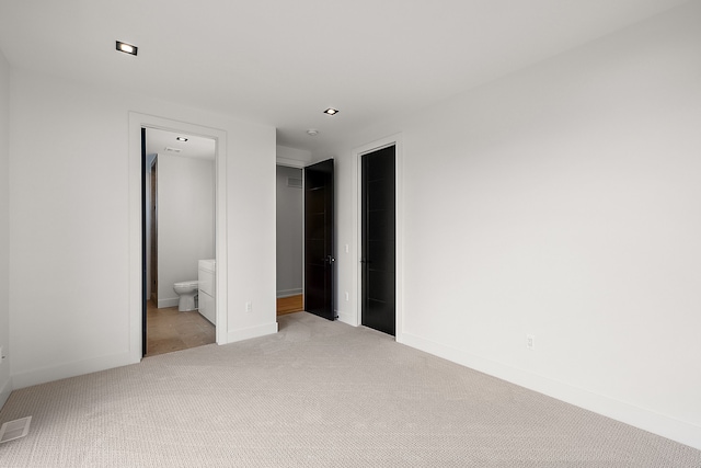 unfurnished bedroom featuring ensuite bathroom and light carpet